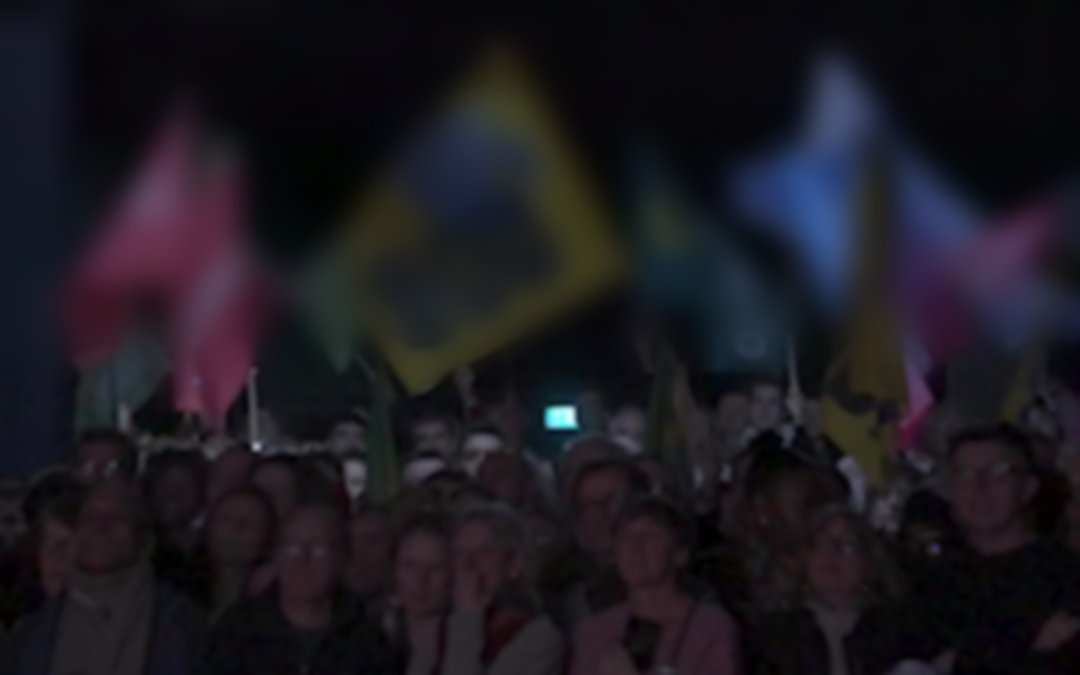 La foule du meeting, drapeaux floutés
